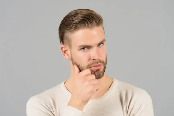 L'uomo barbuto tocca la barba con mano. Macho con capelli eleganti e pelle giovane sana. Un tipo con la faccia rasata e i baffi. Barba toelettatura e cura dei capelli in barbiere. Skincare e mens concetto di bellezza — Foto Stock