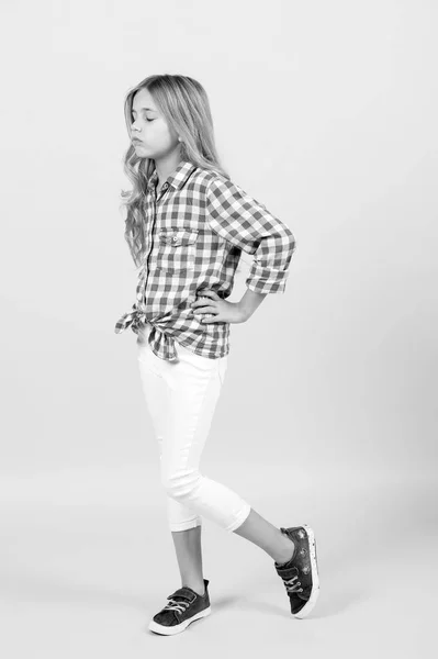 Chica en camisa a cuadros, pantalones, zapatillas de deporte sobre fondo naranja — Foto de Stock
