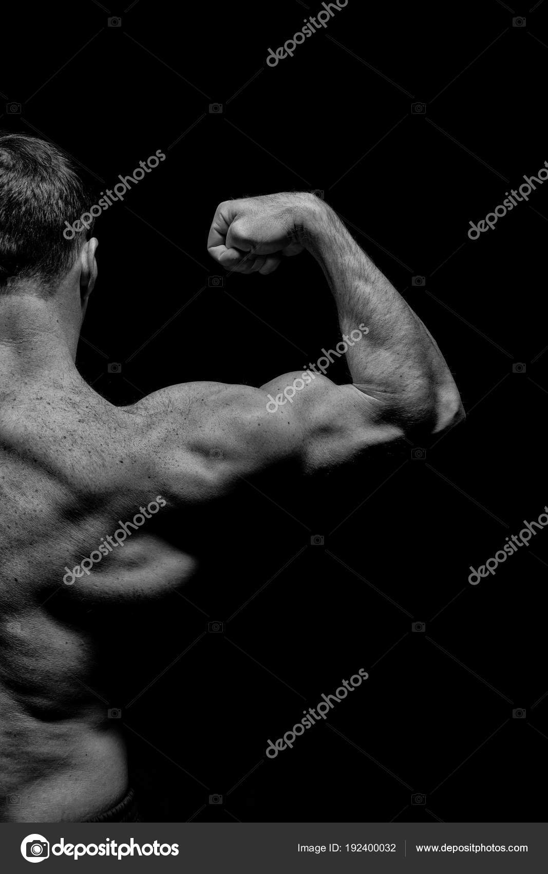Bodybuilder show biceps and triceps. Man athlete with half torso, back view.  Sportsman flex arm muscles. Workout and training activity in gym. Sport  power and bodycare concept, black and white Stock Photo
