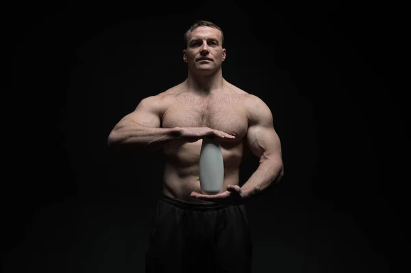Bodybuilder hold shampoo or gel bottle. Man athlete with fit torso and ab. Bodycare and hygiene for sportsman. Spa bath or shower cosmetic after training in gym — Stockfoto