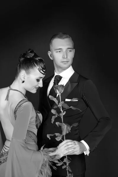 Mujer vestida y macho con esmoquin. Sensual mujer y hombre con flor de rosa. Un par de bailarines de salón enamorados. Celebración de San Valentín. Propuesta de amor y concepto de fecha, blanco y negro — Foto de Stock