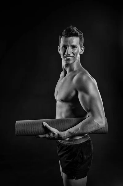 Homem feliz com braços musculosos com bíceps. Sportsman sorriso com tapete de ioga. Atleta sorrindo com corpo sexy e peito. Equipamento de ginástica para treinamento e treino. Esporte ioga e pilates, preto e branco — Fotografia de Stock