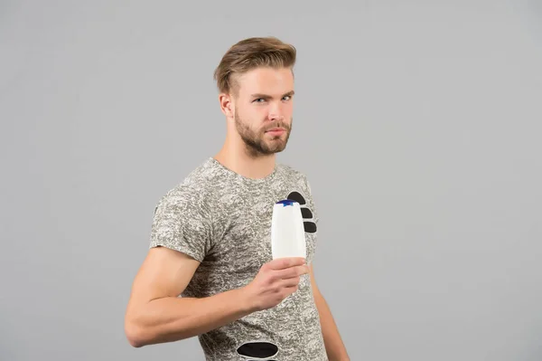 Homme avec shampooing ou bouteille de gel à la main. Macho aux cheveux élégants, coupe de cheveux. Soins de la peau, soins capillaires, santé et hygiène. Hommes beauté et toilettage. Cosmétique pour baignoire spa ou douche, espace de copie — Photo