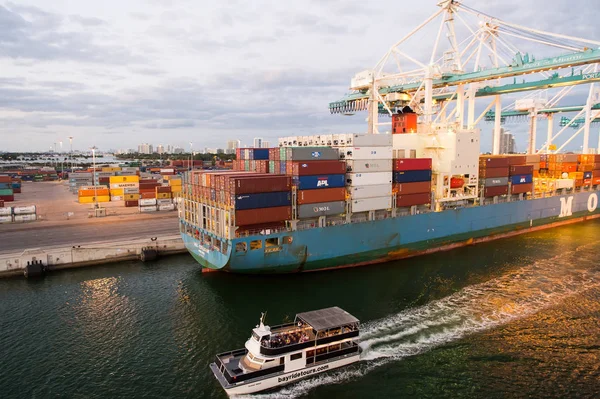 Miami, EUA - 01 de março de 2016: navio de carga e barco de recreio no porto de contêineres marítimos. Porto ou terminal marítimo com contentores e guindastes no céu nublado. Conceito de negócios e férias — Fotografia de Stock