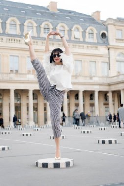 Çekici görünüşlü güzel kız. Esmer saçlı, şehvetli bir kadın. Paris, Fransa 'da kadın topuklu ayakkabıyla poz veriyor. Meydanda güneş gözlüklü manken. Moda ve moda. Yoga ve spor konsepti.