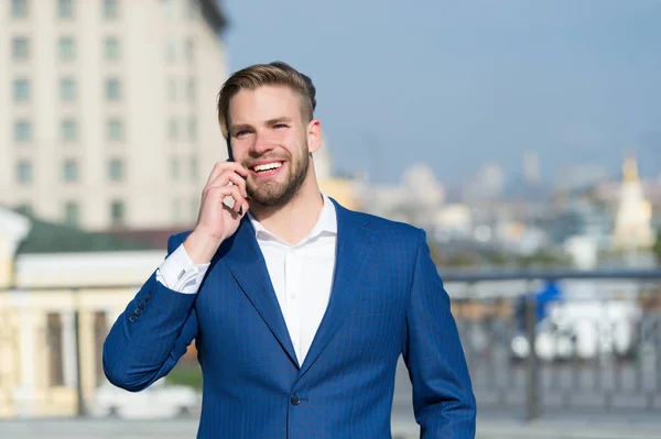 Business-Lifestyle-Konzept. Glücklicher Geschäftsmann mit Smartphone auf sonniger Terrasse. Mann lächelt im formellen Anzug mit Handy draußen. Geschäftskommunikation und neue Technologien — Stockfoto