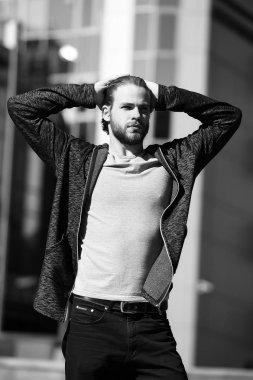 Sakallı adam elleriyle saçına dokunuyor.