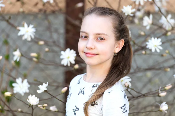 Kind met bloeiende bloemen buiten. Meisje op bloesem in het voorjaar. Schoonheidskind met een frisse look en lang haar. Lente, Pasen en feestdagen viering concept — Stockfoto