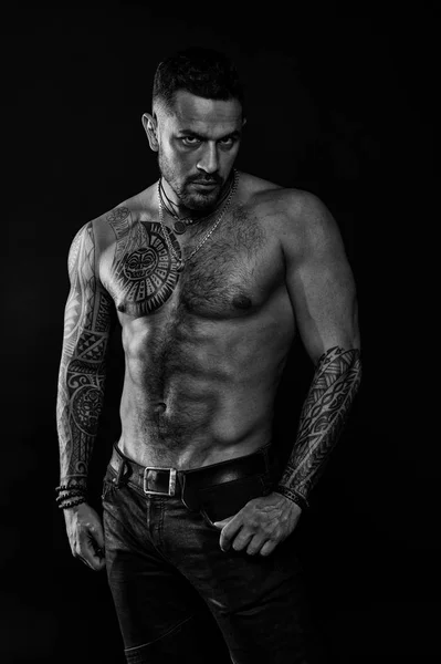 Modello tatuaggio con sei pack e ab. Uomo barbuto con corpo tatuato. Macho con torso nudo sexy in jeans. Sportivo con petto e pancia muscolosi. Sport o fitness e cura del corpo, in bianco e nero — Foto Stock