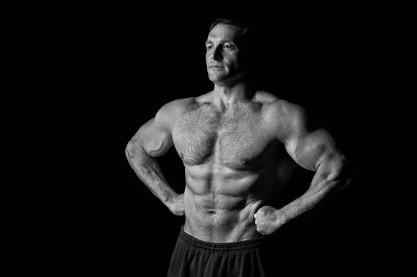 Fisiculturista mostrar bíceps e tríceps. Fisiculturista com seis pack e ab, preto e branco — Fotografia de Stock