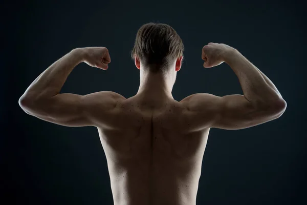 Αθλητής με fit κορμού, πίσω θέα. Άντρας bodybuilder flex μύες του βραχίονα. Αθλητικός τύπος παράσταση δικέφαλου και triceps. Προπόνηση και δραστηριότητα κατάρτισης στο γυμναστήριο. Έννοια δύναμη και αντοχή — Φωτογραφία Αρχείου