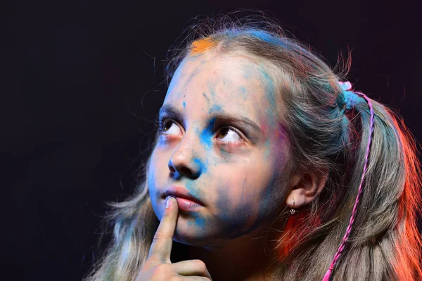 Schoolgirl has paint spots on face. Children and creativity