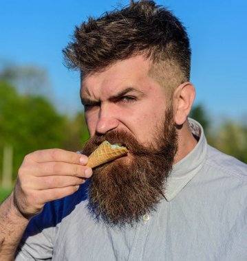 Tatlıya kavramı. Dondurma külahı sakallı adam. Sakal ve bıyık sıkı acımasız yüzünü yiyor dondurma, ısırık gözleme koni, doğa arka plan, defocused olan adam. Sakallı adam zevk dondurma