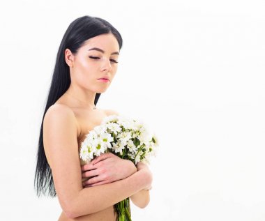 Bayan göğüsler üzerinde beyaz izole çiçekli kapsar. Kadın göğüslerini buket kapaklarla gizleme. Kanser meme kavramının. Sakin yüz çıplak kız papatya çiçeği göğüs önünde tutar.