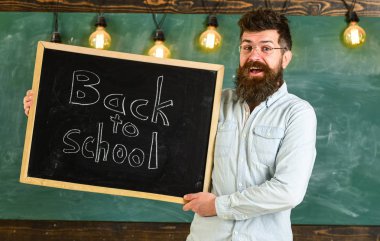 Gözlük öğretmen okul için başlıklı yazı tahtası tutar. Eğitim ve eğitim kavramı. Sakal ve bıyık mutlu yüz memnuniyetle öğrencilerin, kara tahta arka plan ile adam