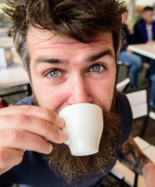 Kille med resten med espressokaffe. Fika koncept. Hipster på lugna ansikte dricka kaffe utomhus, närbild. Mannen med skägg och mustasch innehar kopp kaffe medan du kopplar av på caféets terrass — Stockfoto