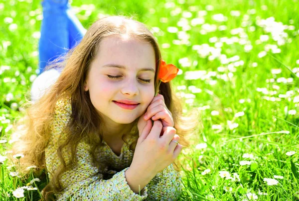 背景に草地の草の上に横たわる少女。夢のような顔の女の子が赤いチューリップの花を保持して、香りをお楽しみください。子供では、春の晴れた日、花と草原で横になってお楽しみください。季節性アレルギーの概念 — ストック写真