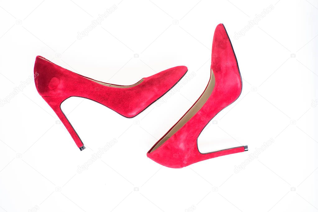 Luxury footwear concept. Footwear with thin high heels, stiletto shoes, top view. Shoes made out of red suede on white background, isolated. Pair of fashionable high heeled pump shoes