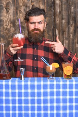 Adam ahşap arkaplanda kokteyli işaret ediyor..
