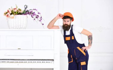 Yakışıklı sakallı taşıyıcı retro piyano beyaz arka plan üzerinde izole yanında poz. Yorucu iş küçük ara