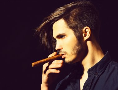 Ciddi sakallı adam puro içiyor.