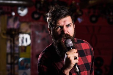 Sakallı ve bıyıklı bir müzisyen karaokede şarkı söylüyor..