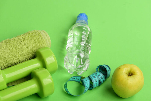 Dumbbells in bright green color, water bottle, measure tape, towel