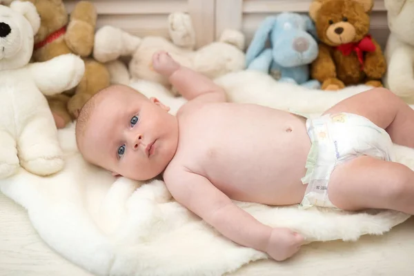 Säugling mit blauen Augen und neugierigem Gesicht auf heller Decke — Stockfoto