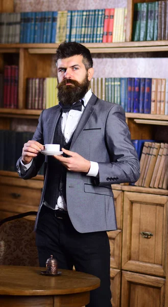 Lawyer stands in luxury interior with cup of tea or coffee.