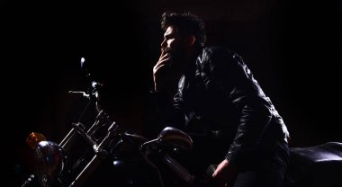 Gece yarışçısı kavramı. Sakallı, motorcu karanlık, siyah arka planda motorlu bisiklet üzerinde oturan deri ceketli adam. Maço, vahşi motorcu deri ceket sürme motosiklet gece zaman, kopya alanı
