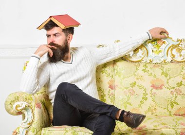 Maço kafasına, çatı gibi açık kitap ile oturuyor. Sıkıcı edebiyat kavramı. Sakal ve bıyık oturur Barok tarzı kanepe, beyaz duvar arka plan üzerinde olan adam. Adam sıkılmış, eski sıkıcı kitap okuma bıkmış