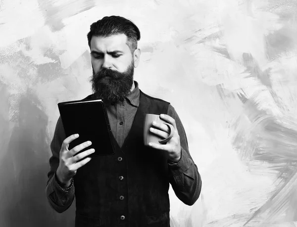 Bärtiger brutaler kaukasischer Hipster mit Kaffeetasse und schwarzem Notizbuch — Stockfoto