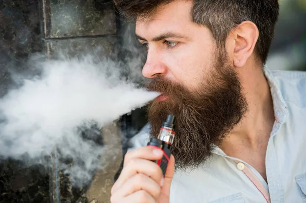 Stressed man smoking e-cigarette. Side view bearded man inhaling vape. Stress relief and relaxation concept