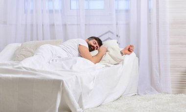 Sakin yüz beyaz çarşafımda yatıyor adam, yastık. NAP ve siesta kavramı. Adam arka plan üzerinde battaniye, beyaz perdeler ile kaplı yatağa atma. Maço sakal uyku ile rahatlatıcı, nap, sahip rest