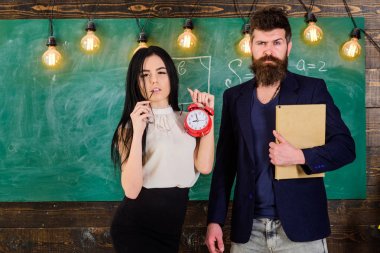 Sakallı adam tutun kitap ve seksi kız öğretmen çalar saat, kara tahta arka plan tutar. Bayan öğretmen ve sıkı öğretmen disiplin ve okul kurallarında önem veriyoruz. Okul kuralları kavramı