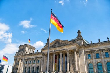 German flags waving in the wind at famous Reichstag building, seat of the German Parliament (Deutscher Bundestag), on a sunny day with blue sky and clouds, central Berlin Mitte district, Germany clipart