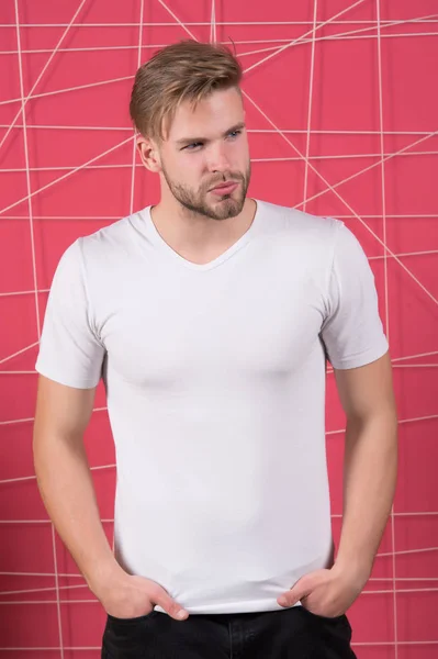 ポケットに手で立って若いヨーロッパ人男性,ピンクの背景にコピースペースのための空白の白いTシャツを着て — ストック写真