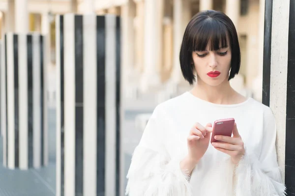 Nova tecnologia para a vida moderna. Mulher com lábios vermelhos usar no smartphone em Paris, França. Mulher com cabelo morena segurar telefone celular. Menina de beleza com olhar sexy. Modelo de moda com dispositivo móvel — Fotografia de Stock