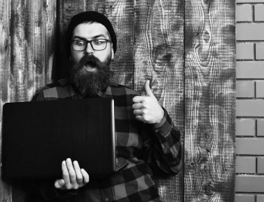 Kaba sakallı, beyaz tenli hippi dizüstü bilgisayar tutuyor.