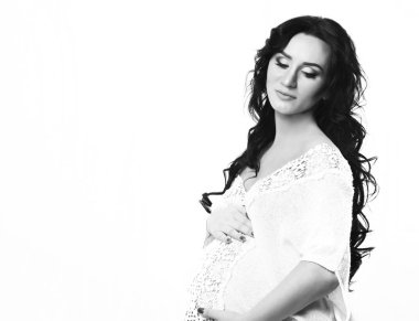 Güzel, hamile bir kadın karnını okşuyor.