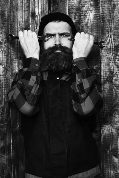 Bearded brutal caucasian mechanic holding metallic wrenches — Stock Photo, Image