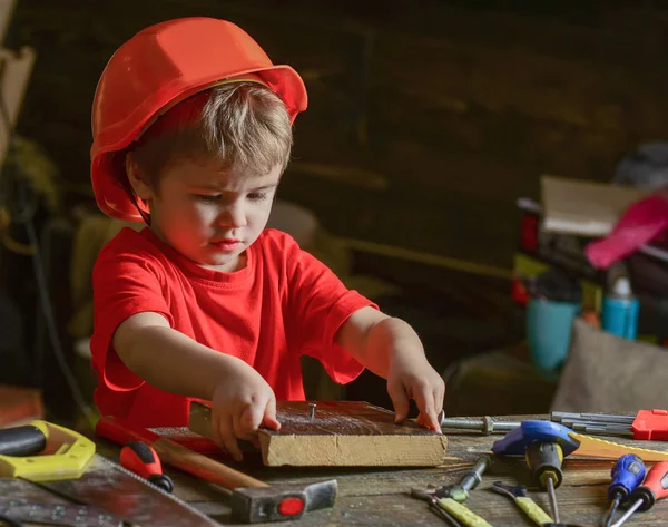 어린이 헬멧 작성기 또는 예, 복구 또는 handcrafting 재생 귀여운. 워크숍에서 가정에서 바쁜 얼굴 놀이에서 유아 Handcrafting 개념입니다. 나무 보드에 아이 보가 망치로 못 — 스톡 사진