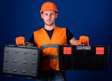 Kask, kask içinde adam araç kutusu ve araç, mavi arka plan ile bavul tutar. İşçi, repairer, tamirci, Oluşturucu düşünceli yüzündeki iş için ekipman seçimi. Araç kutusu ve ekipman kavramı