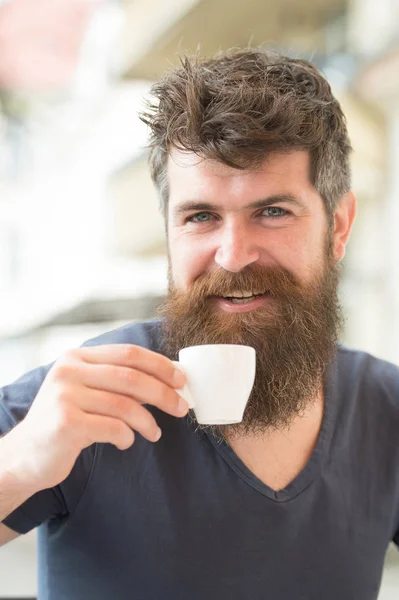 L'homme barbu tient une tasse à expresso, boit du café. Concept de pause café. Homme à longue barbe semble gai et détendu. Homme avec barbe et moustache sur le visage souriant heureux, fond clair, déconcentré — Photo