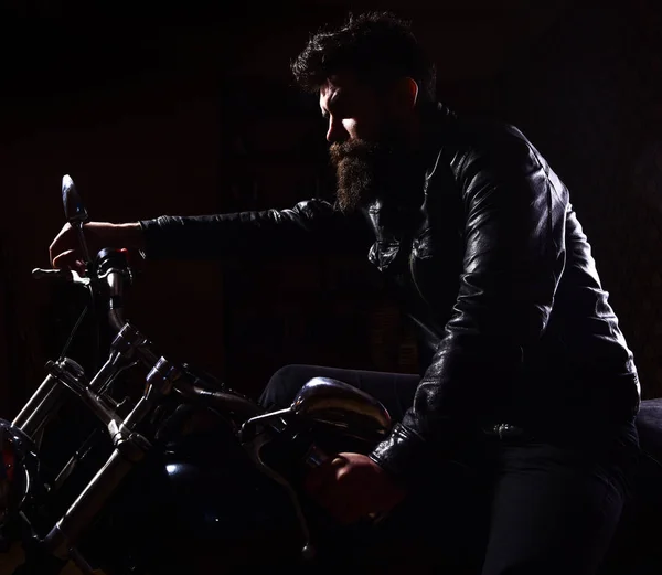 Macho, motociclista brutal em jaqueta de couro andar de moto à noite, espaço cópia. Homem com barba, motociclista de jaqueta de couro sentado em moto no escuro, fundo preto. Conceito de piloto noturno — Fotografia de Stock