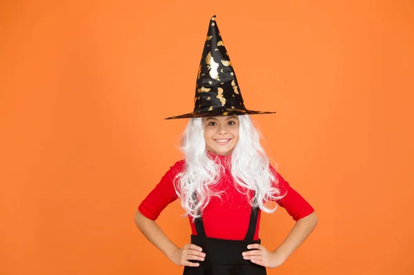 Élvezem a bulit. Rejtélyes boszorkány. Kisgyerek boszorkány kalap. Csokit vagy csalunk. természetfeletti elbűvölő ősz haj. gyerek narancs háttér. Boldog Halloweent! Varázslatos. mosolygós kislány halloween party — Stock Fotó