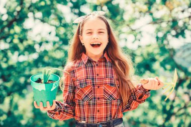 Bahçıvanlık barışçıl meditasyon işidir. Bahçıvanlık dersleri. Bahçe bakımı. Ekoloji eğitimi. Çiçek eken küçük bir kız. Ekim mevsimi. Sevimli çocuk çiçek saksısı ve çapa bahçe aleti tutuyor.