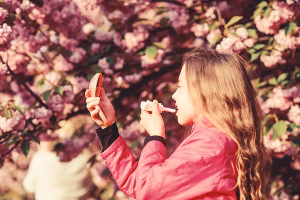 Smell of tender bloom. Sakura flower concept. Natural cosmetics for skin. Girl in cherry flower. Kid with lipstick makeup. Small girl child in spring flower bloom. Gorgeous flower and female beauty