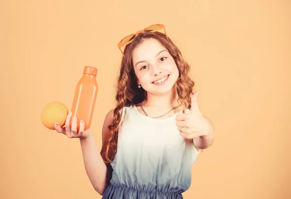 Gelukkige kindertijd. Natuurlijke vitamine bron. Kid meisje eten oranje fruit en drinken sinaasappelsap. Vitamine voeding. Fashion Kid zonnebrillen drinken verfrissend vitamine SAP. Gezondheidszorg. Zomer vitamine dieet — Stockfoto