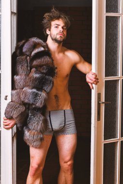 Lüks yaşam tarzı ve refah. Lüks statü sembolü. Yatak odası kapıdan gelen seksi maço tousled saç. Zenginlik ve lüks konsepti. Bekarlığa veda zengin sevgilisi. Adam çekici poz kürk manto çıplak vücut üzerinde